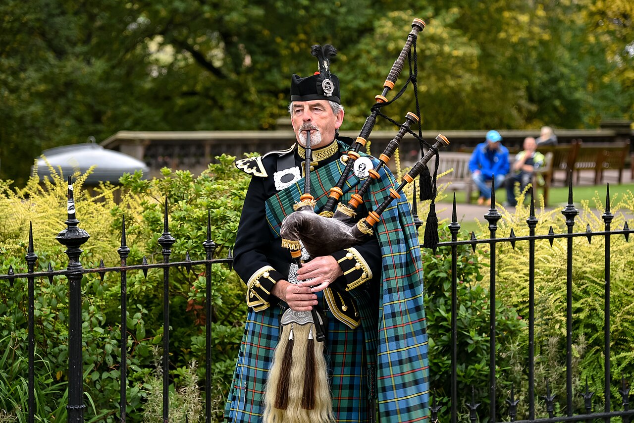 Scottish Highland piper in tartan kilt playing bagpipes in Edinburgh